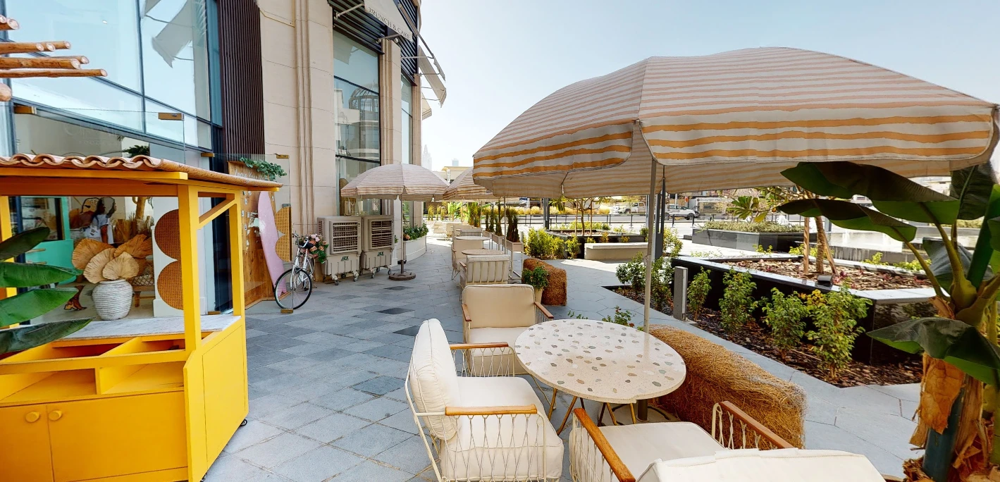 Striped umbrellas over outdoor seating at Brunch & Cake Wasl 51.