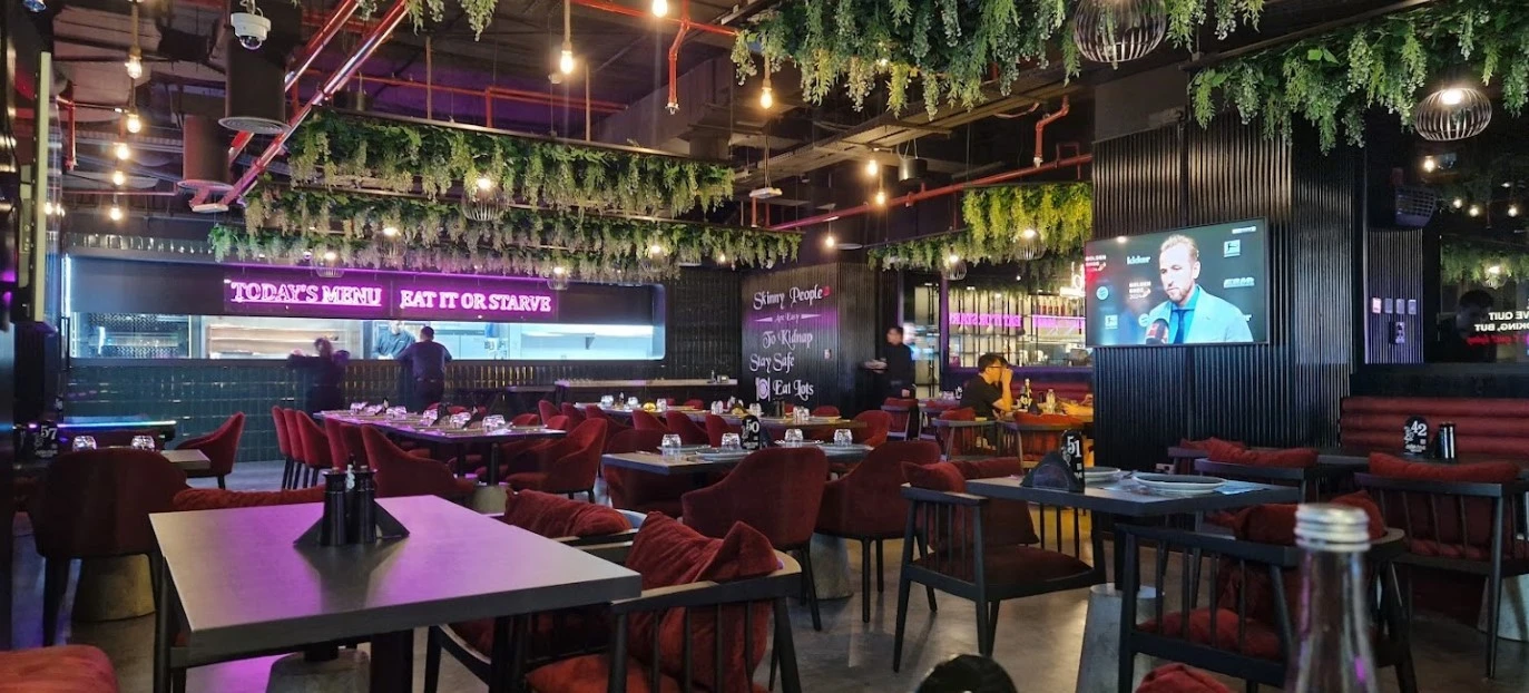 Charcoal Garden Restaurant Dubai, vibrant interior with greenery and neon signs.