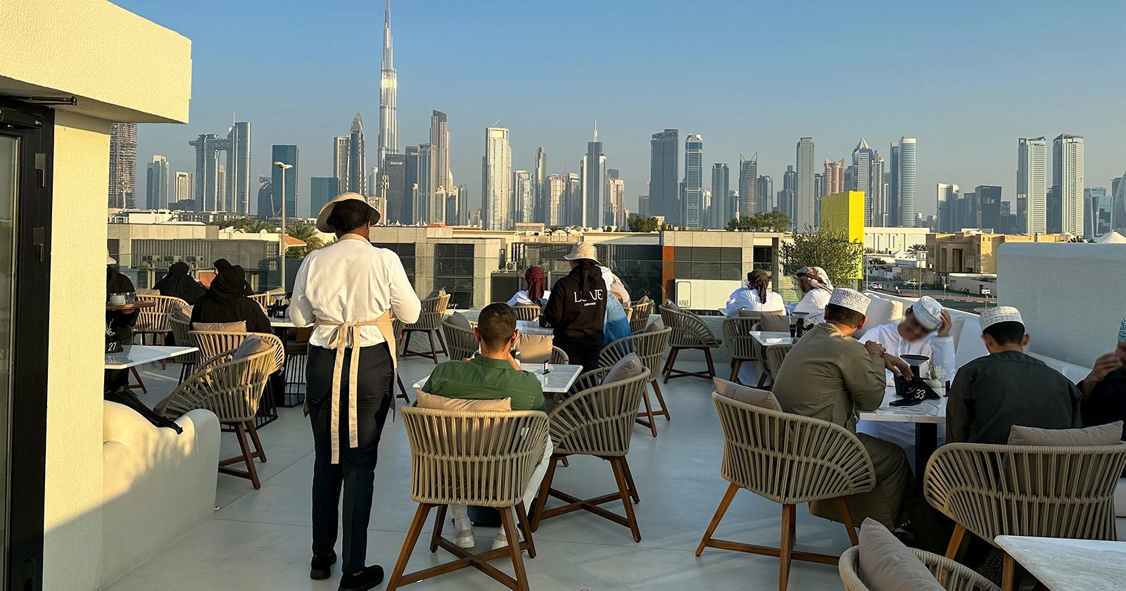 Lune Lounge rooftop with Dubai skyline view, patrons dining outdoors.