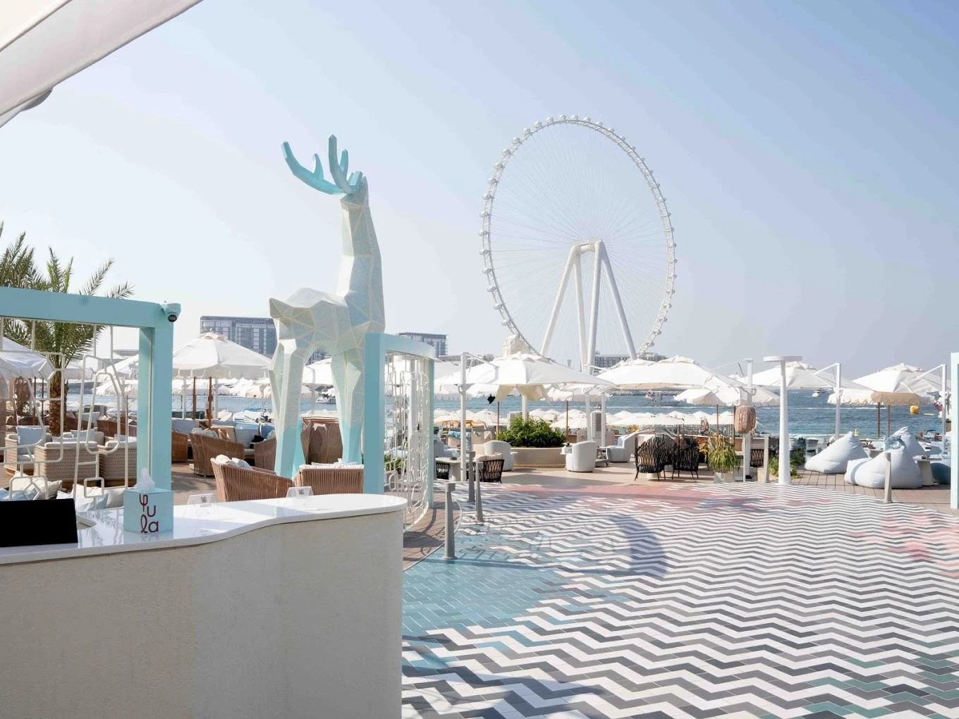 Yula Lounge Dubai, outdoor seating, geometric deer sculpture, Ferris wheel view.