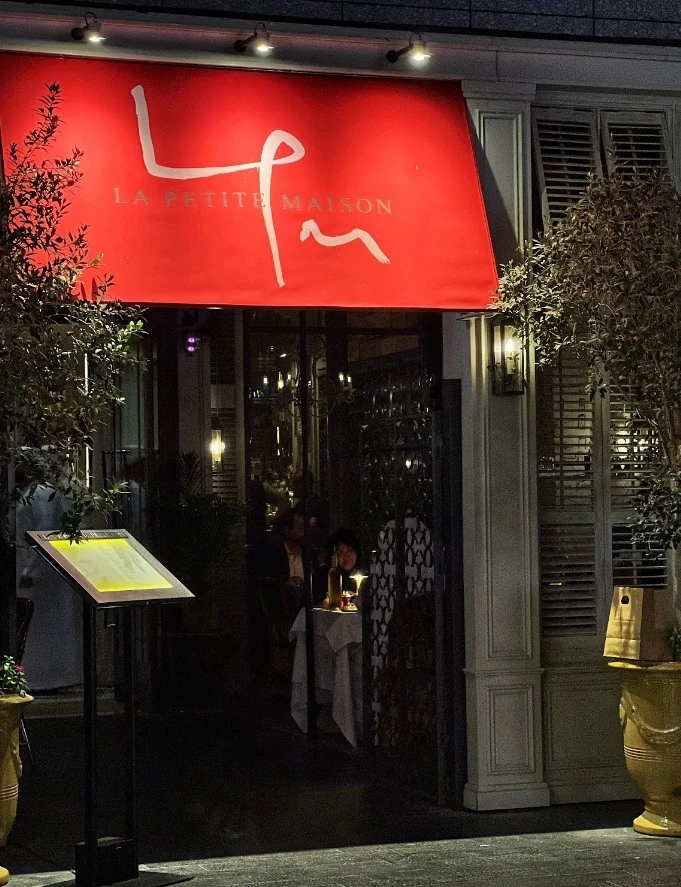 Entrance of La Petite Maison restaurant, Dubai, with red canopy.