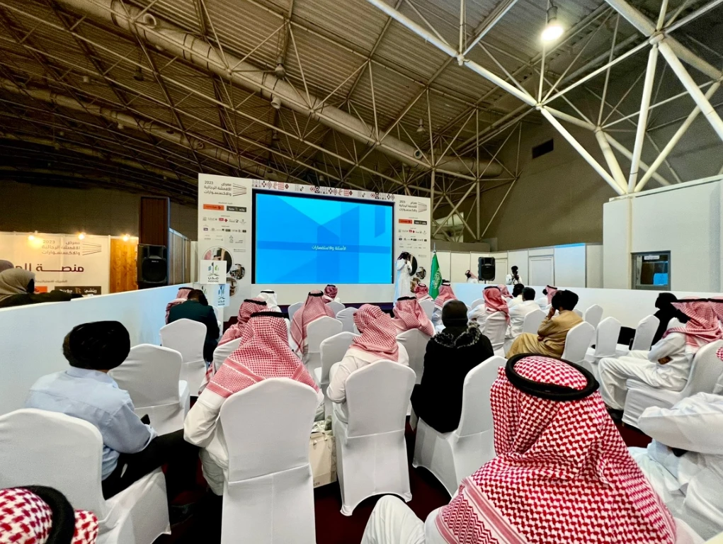 Audience at Riyadh International Convention Center event, large screen visible.