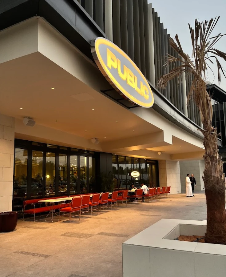 PUBLIC Restaurant Riyadh entrance with outdoor seating and palm tree.