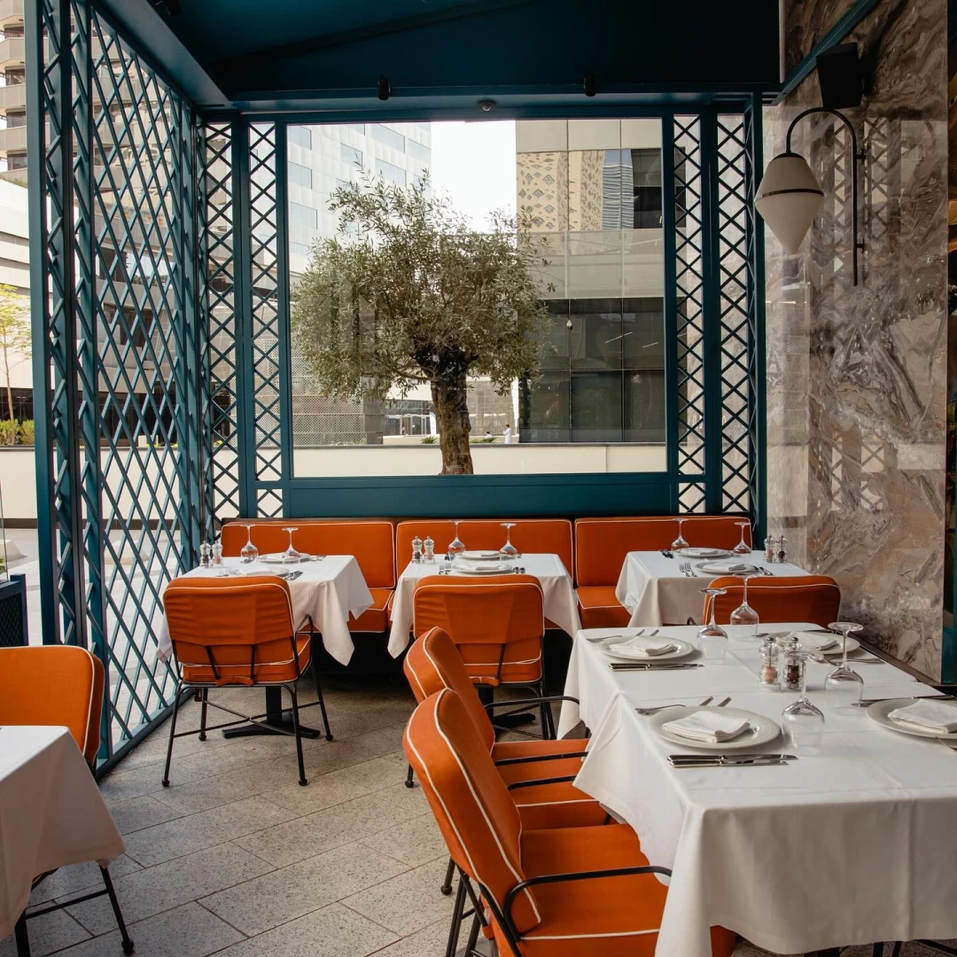 Outdoor dining area at Il Baretto Restaurant, Riyadh with orange chairs.
