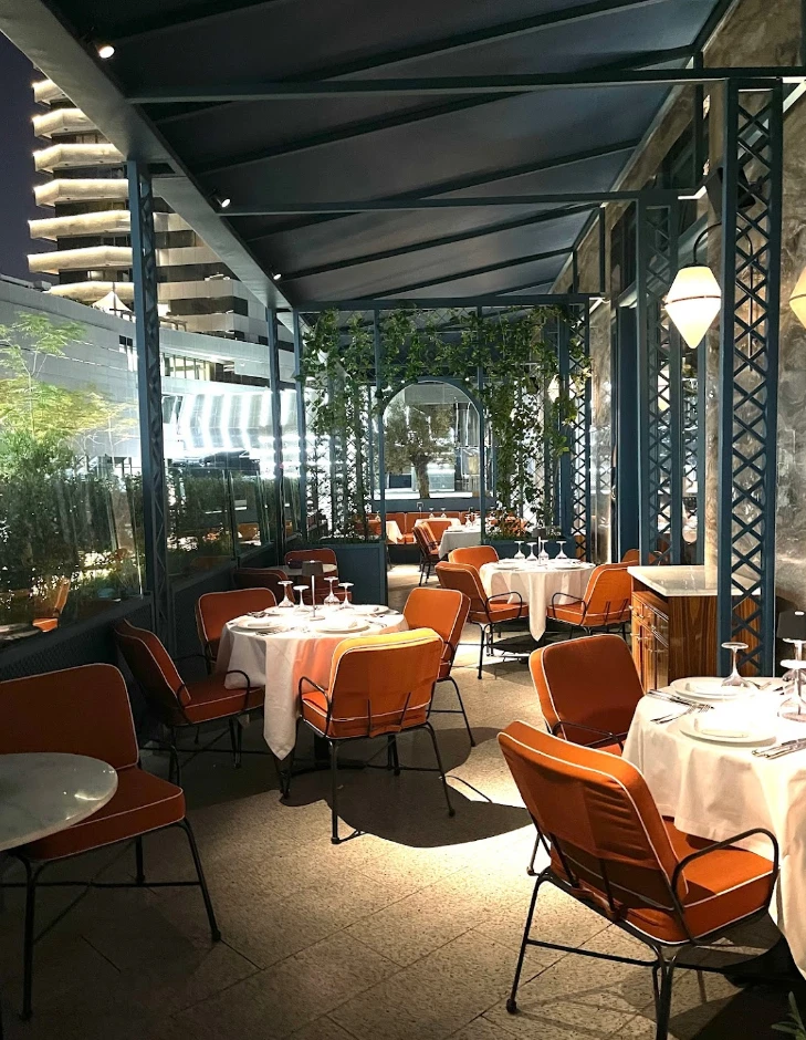Outdoor dining area at Il Baretto Restaurant, Riyadh, with orange chairs.