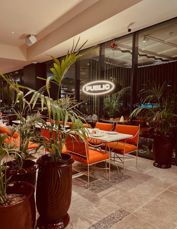 PUBLIC Restaurant Riyadh, elegant dining area with orange seating and plants.
