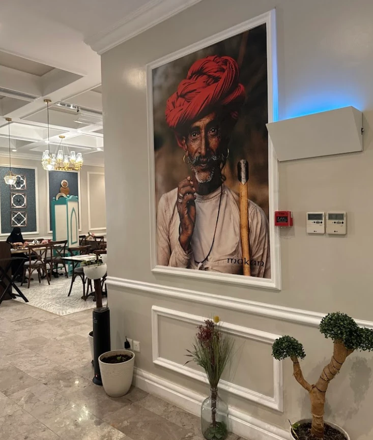 Interior of Makan Indian Restaurant Jeddah with large portrait on wall.