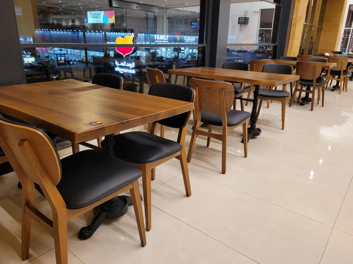 Al Romansiah Restaurant Makkah, wooden tables, black chairs, glass window view.