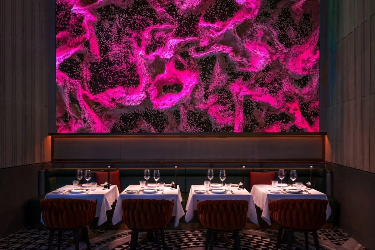 Elegant dining area with vibrant pink abstract wall, Zenon Restaurant Dubai.