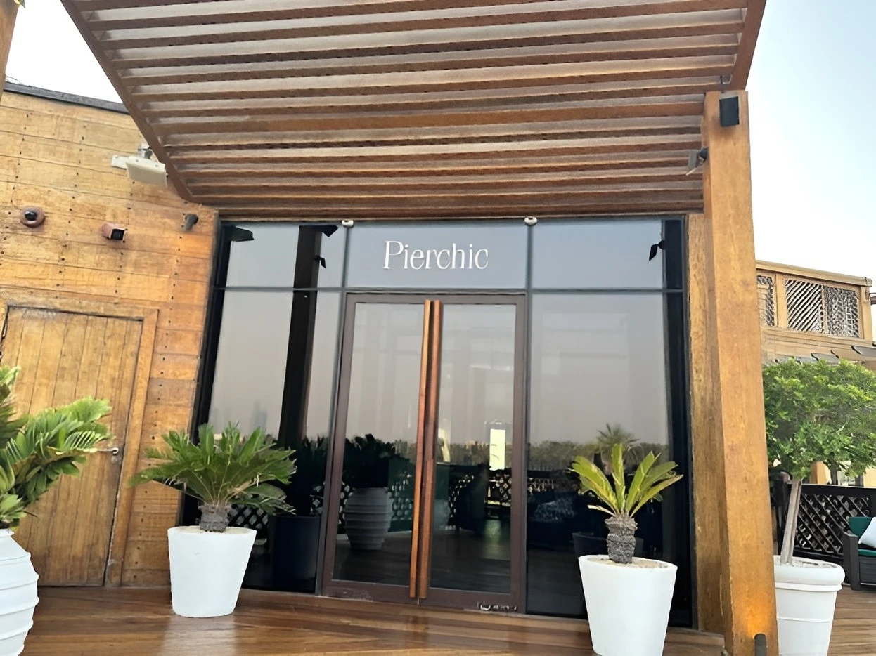 Entrance of Pierchic Restaurant, Dubai with potted plants.