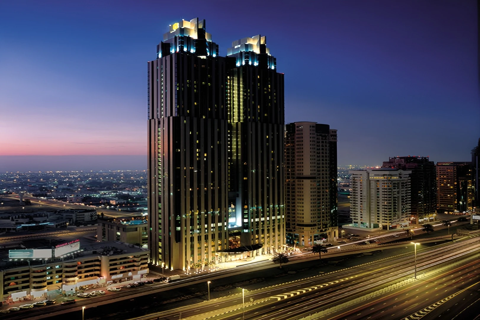 Shangri-La Dubai hotel illuminated at dusk with city skyline view.
