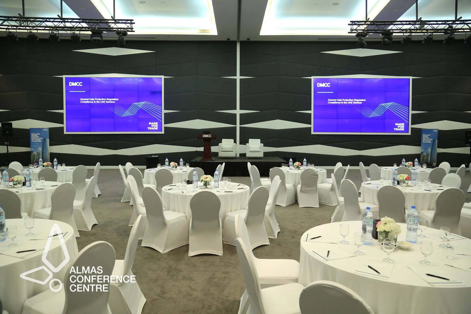 Almas Conference Centre Dubai, round tables, stage with screens.