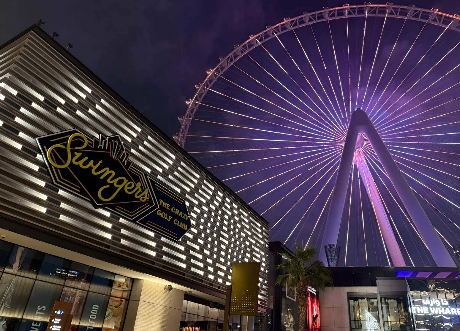 Swingers The Crazy Golf Club Dubai with illuminated Ferris wheel backdrop.
