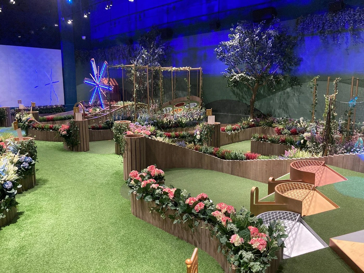 Indoor mini-golf course with vibrant flowers at Swingers Dubai.