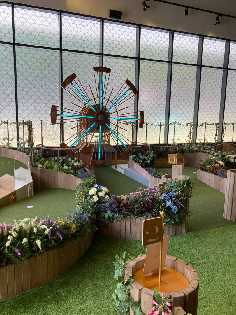 Indoor mini-golf course with Ferris wheel at Swingers The Crazy Golf Club Dubai.