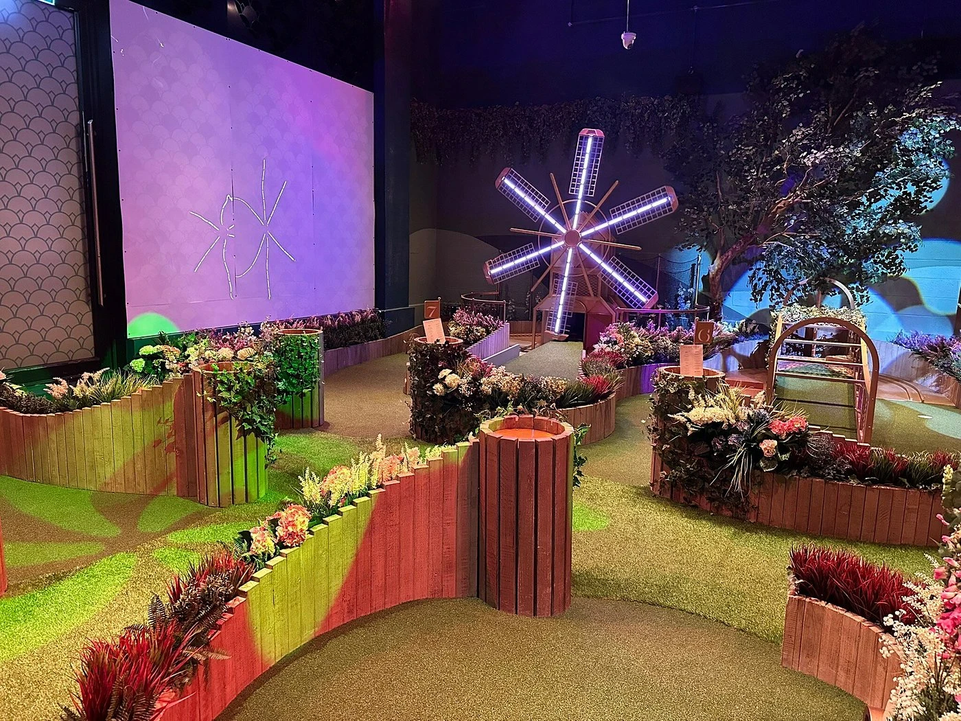 Illuminated windmill on vibrant mini-golf course, Swingers Dubai.