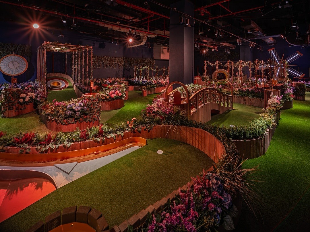 Indoor mini-golf course with vibrant flowers, Swingers The Crazy Golf Club Dubai.