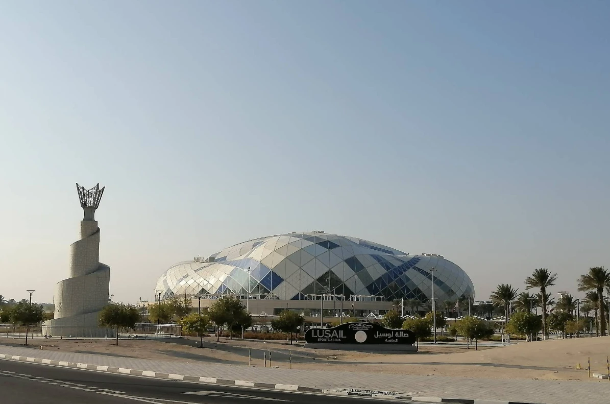 Lusail Multipurpose Hall exterior with sculpture, Doha skyline visible.