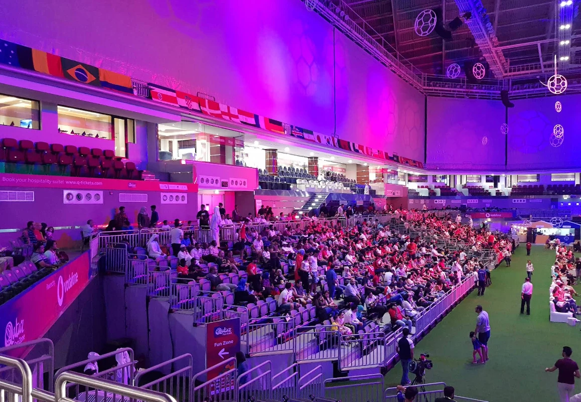 Crowd at Ali Bin Hamad Al Attiyah Arena, Doha, under purple lights.