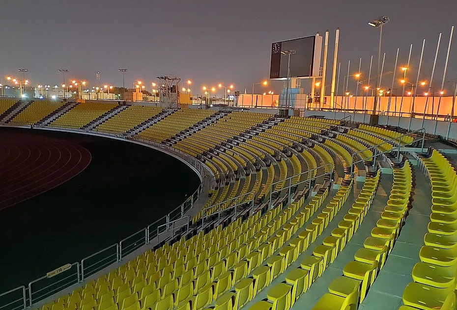 Empty yellow seats at Suheim Bin Hamad Stadium, Doha, at night.