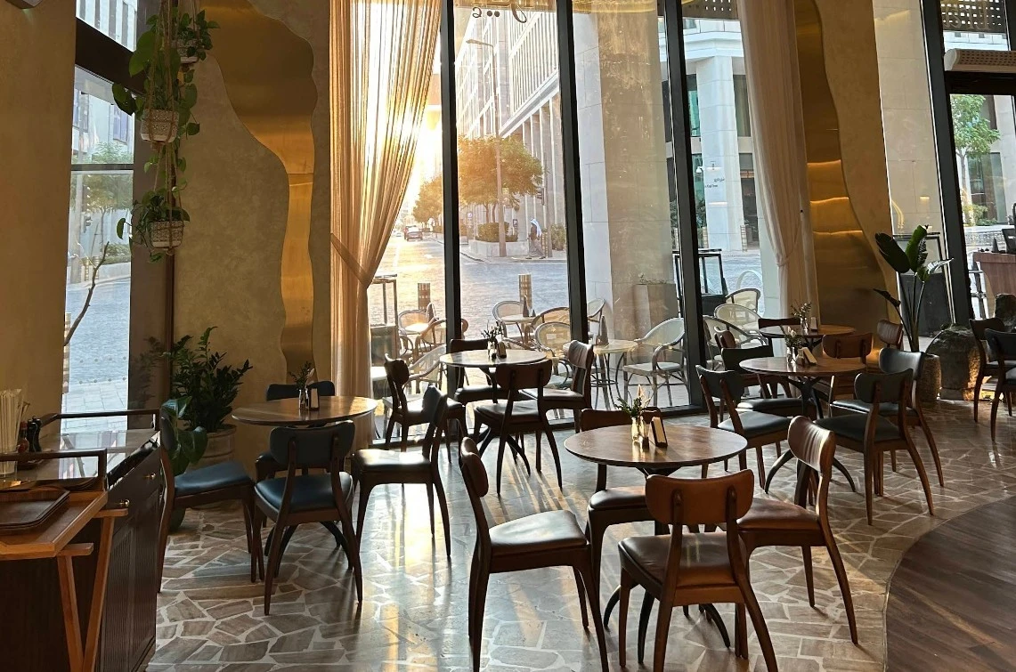 Sunlit dining area at Era Restaurant Doha with wooden tables.