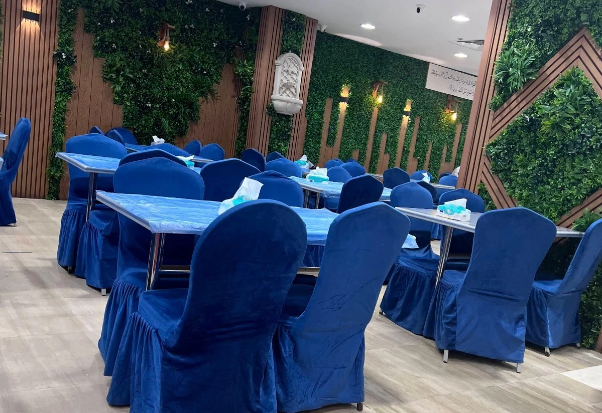 Zaitoon Restaurant Madinah interior with blue chairs and green walls.