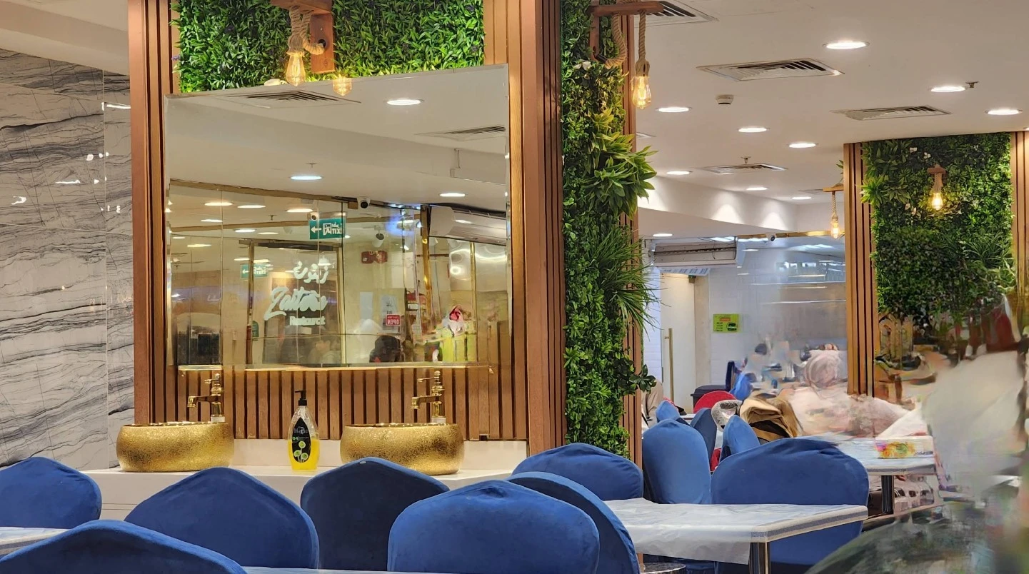 Zaitoon Restaurant Madinah interior with blue chairs and green decor.
