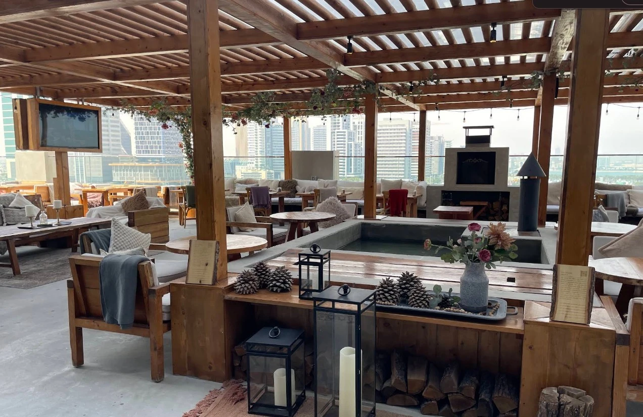 The House Restaurant Lusail rooftop with wooden decor and city view.