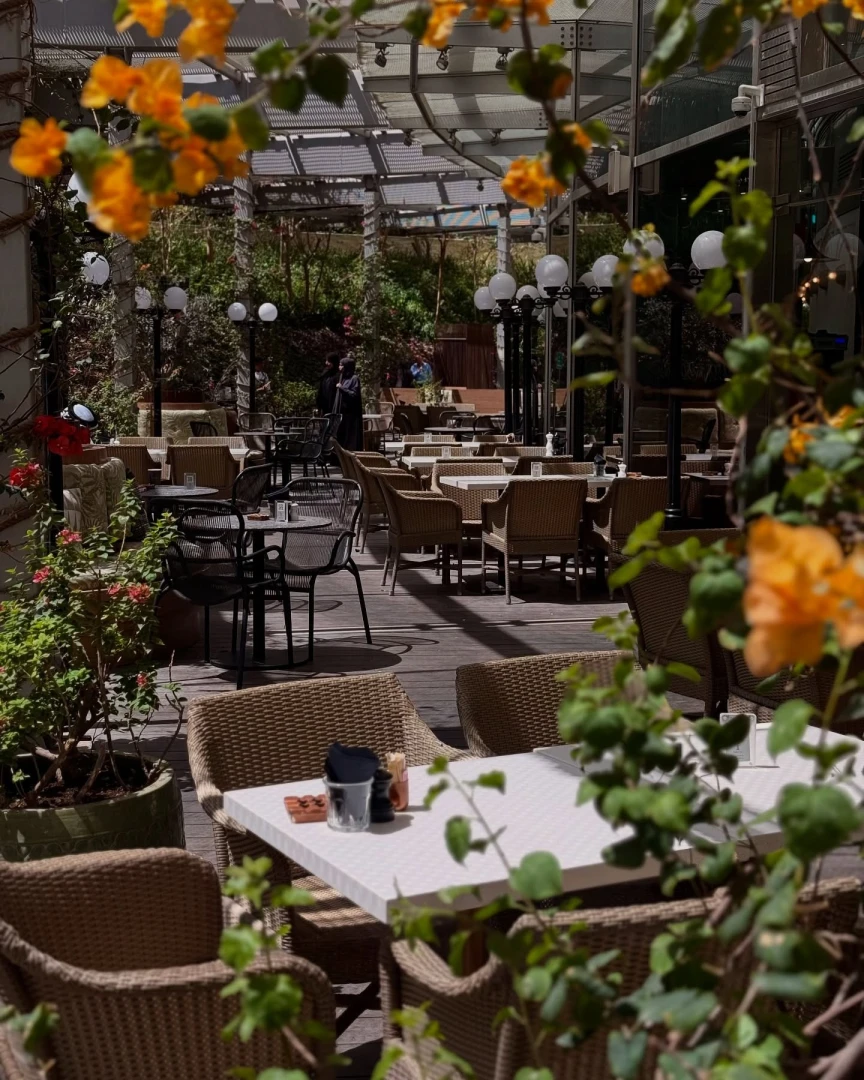 Outdoor seating at Twisted Olive & Naama’s Garden, Doha, with flowers.