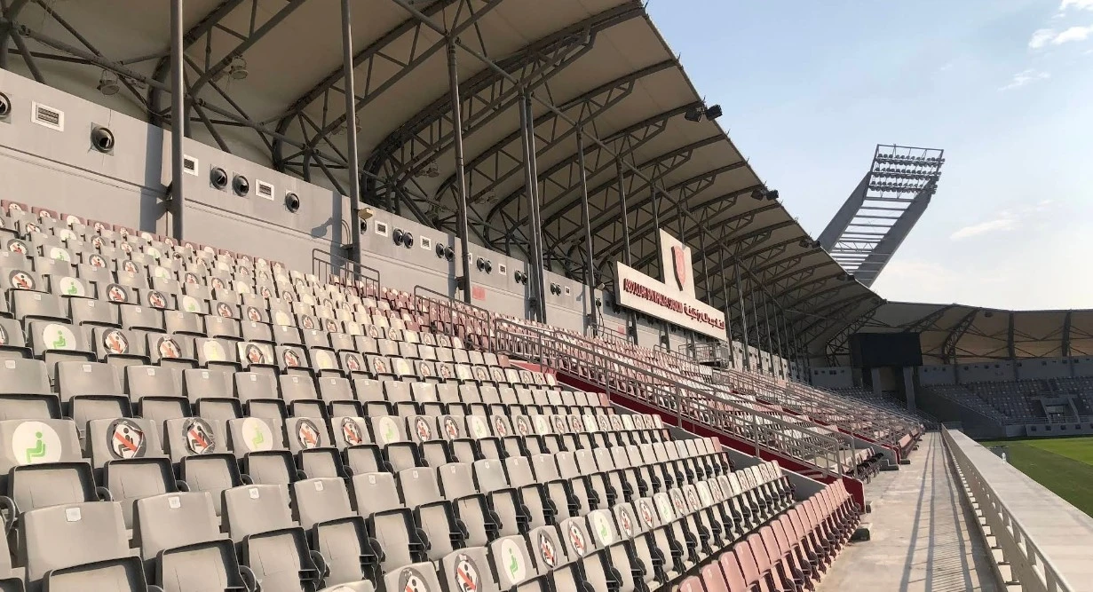 Empty stands at Abdullah Bin Khalifa Stadium, Doha under clear sky.