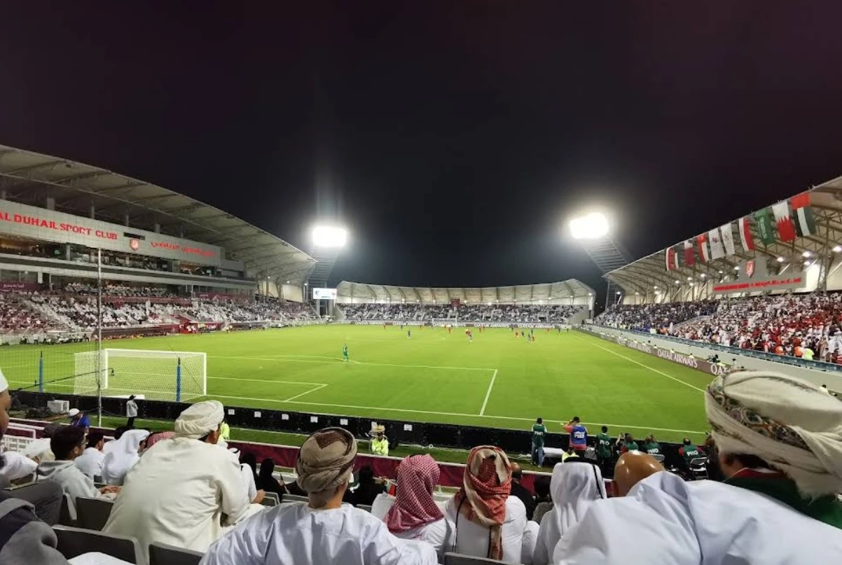Night match at Abdullah Bin Khalifa Stadium, Doha, with spectators.