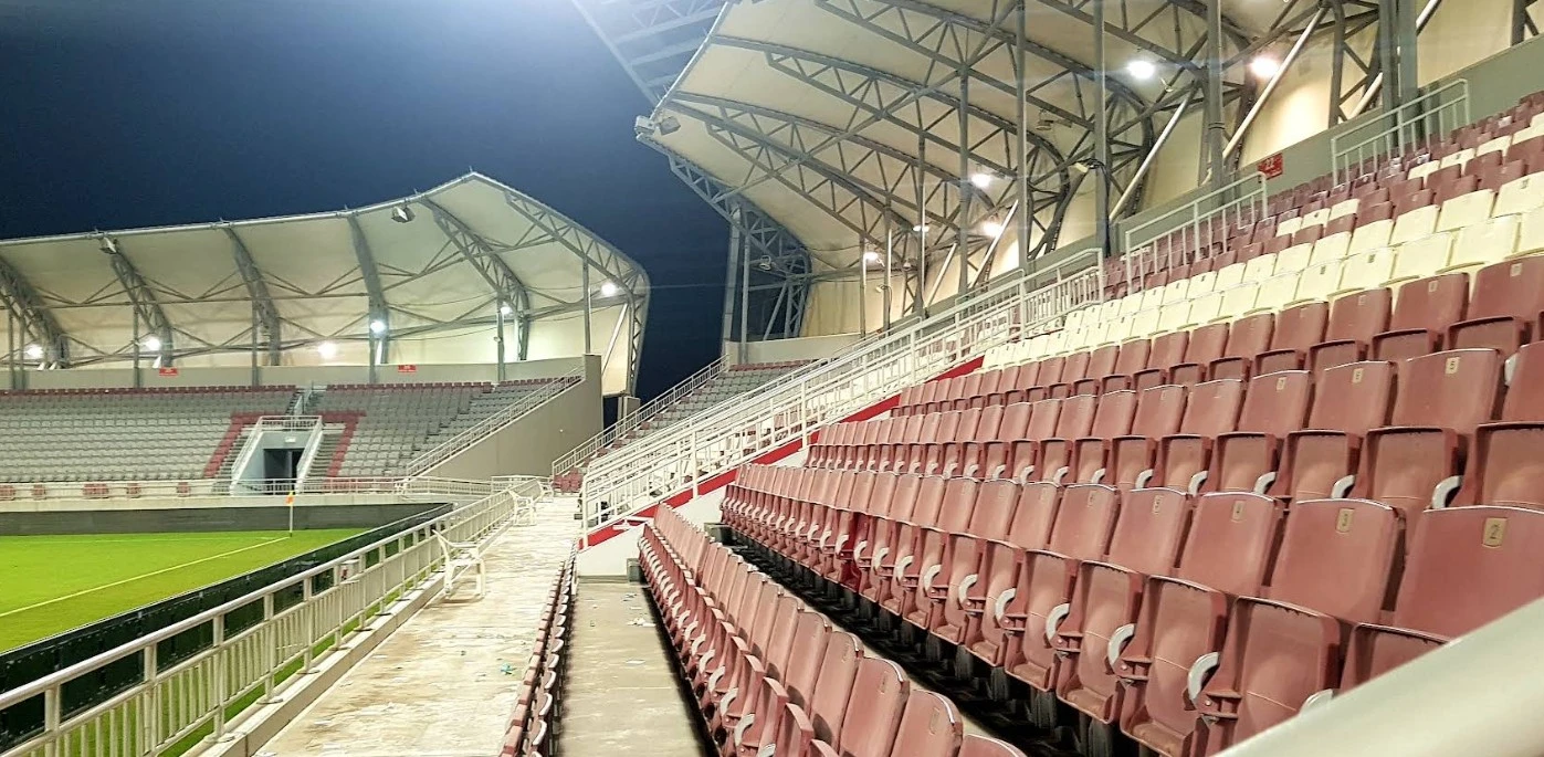 Empty seating area at Abdullah Bin Khalifa Stadium, Doha, at night.