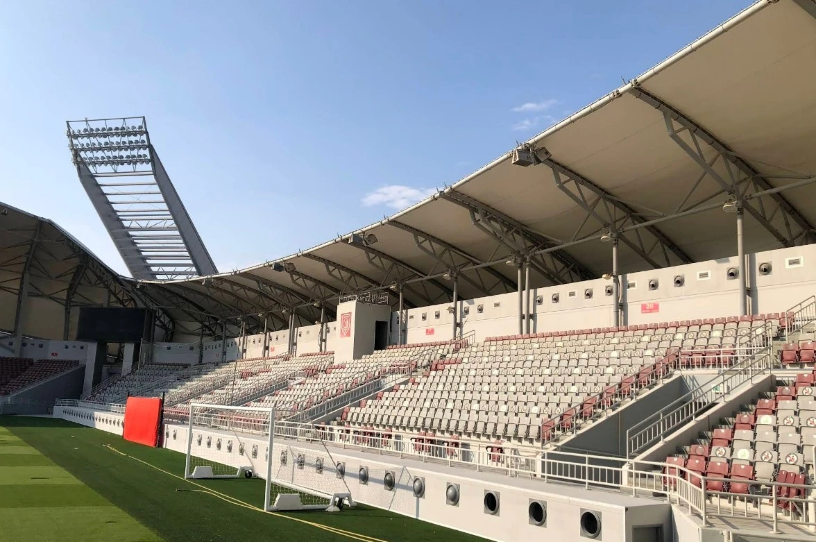 Abdullah Bin Khalifa Stadium seating area, Doha, under clear blue sky.