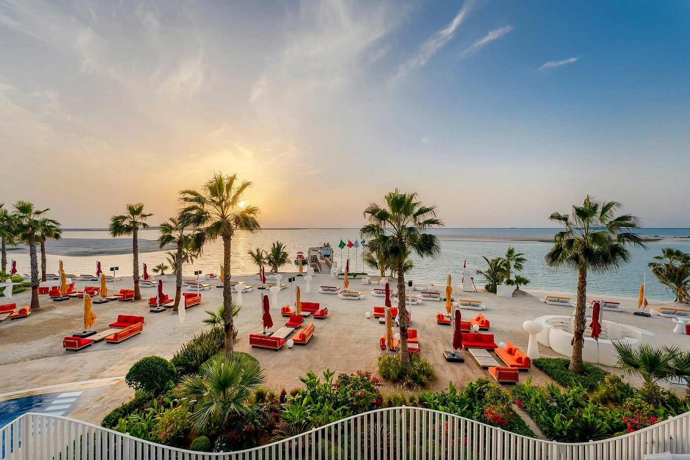 Sunset view at Voco Monaco Dubai beach with palm trees.