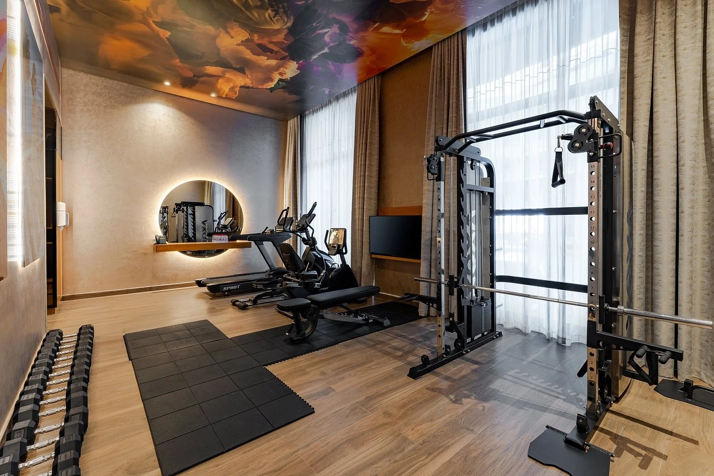 Modern gym at Voco Monaco Dubai with equipment and mirrored wall.