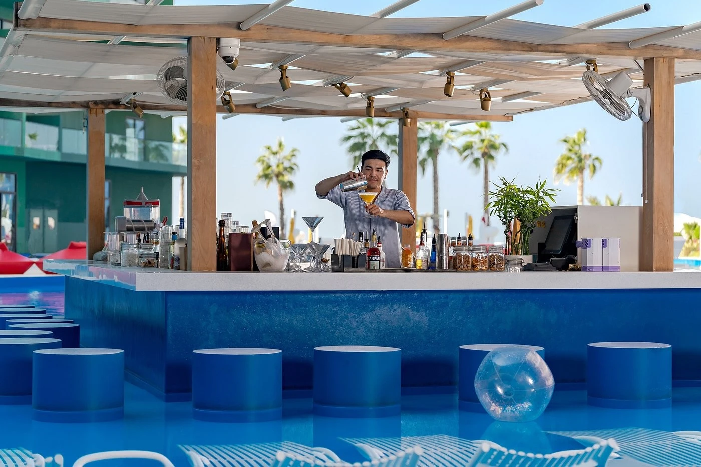 Bartender mixing drinks at Voco Monaco Dubai's lagoon pool bar.