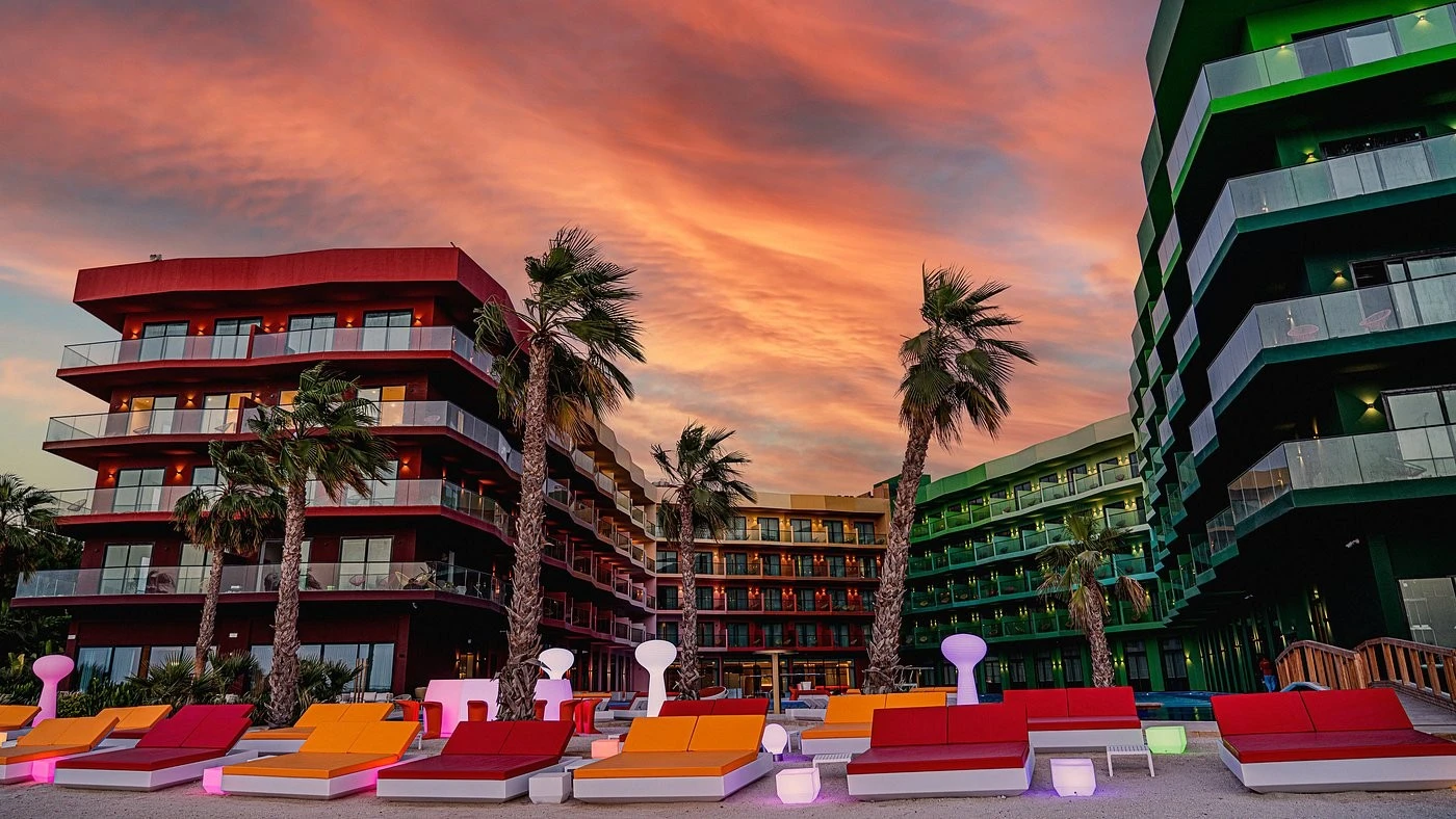 Voco Monaco Dubai exterior with colorful sunset and palm trees.