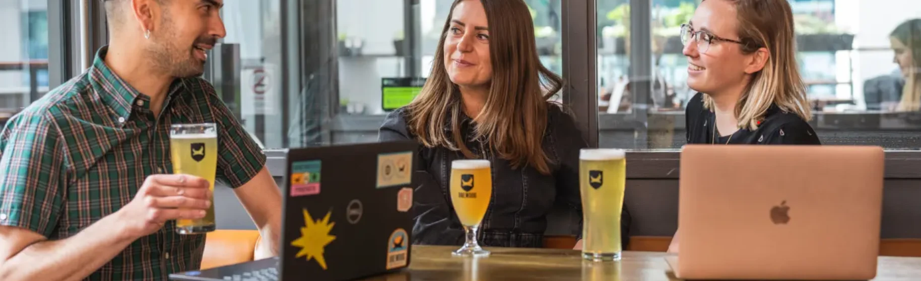 People coworking at BrewDog Bluewaters, Dubai with drinks and laptops.