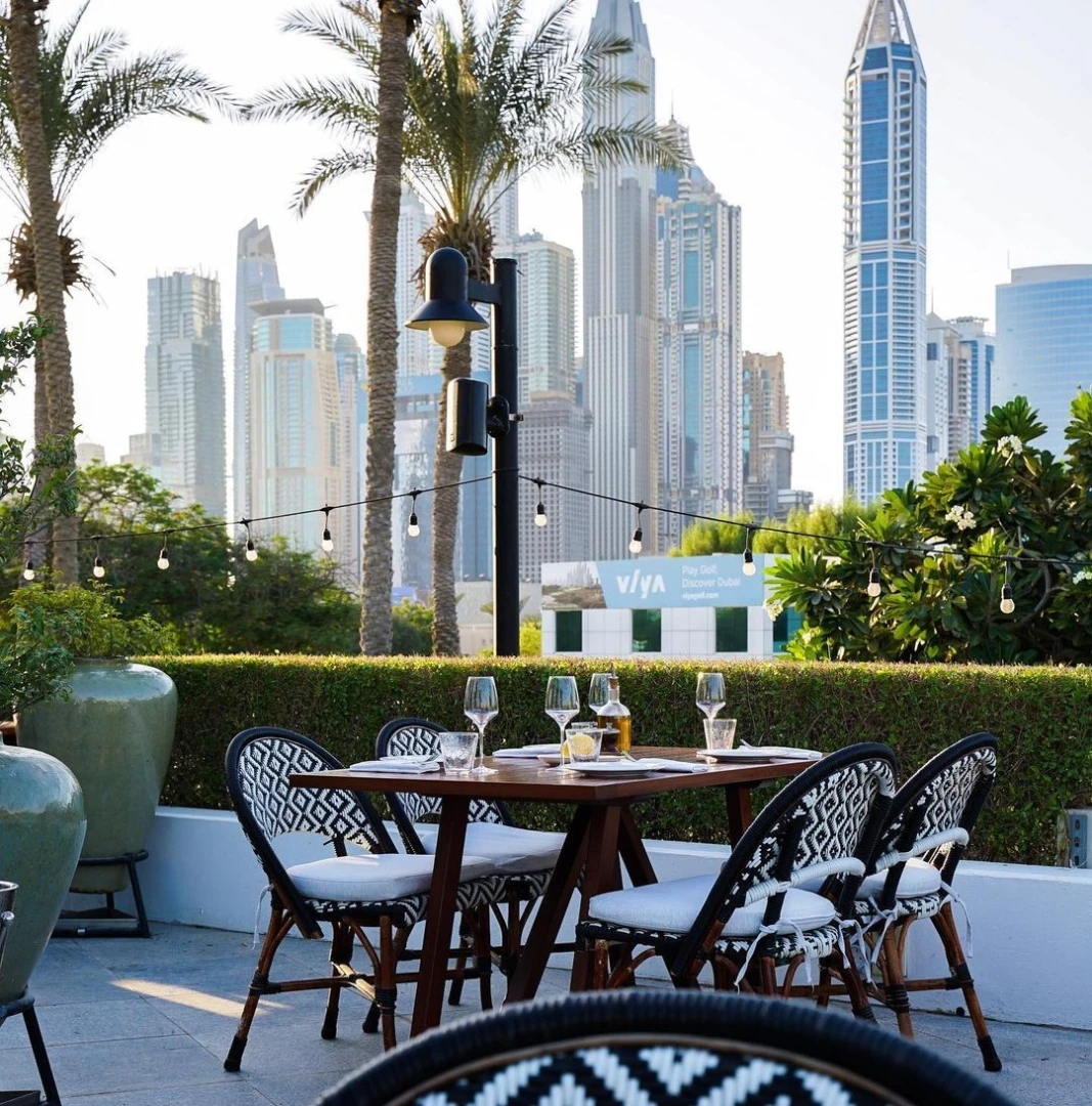 Outdoor dining at Carine Restaurant Dubai with city skyline view.
