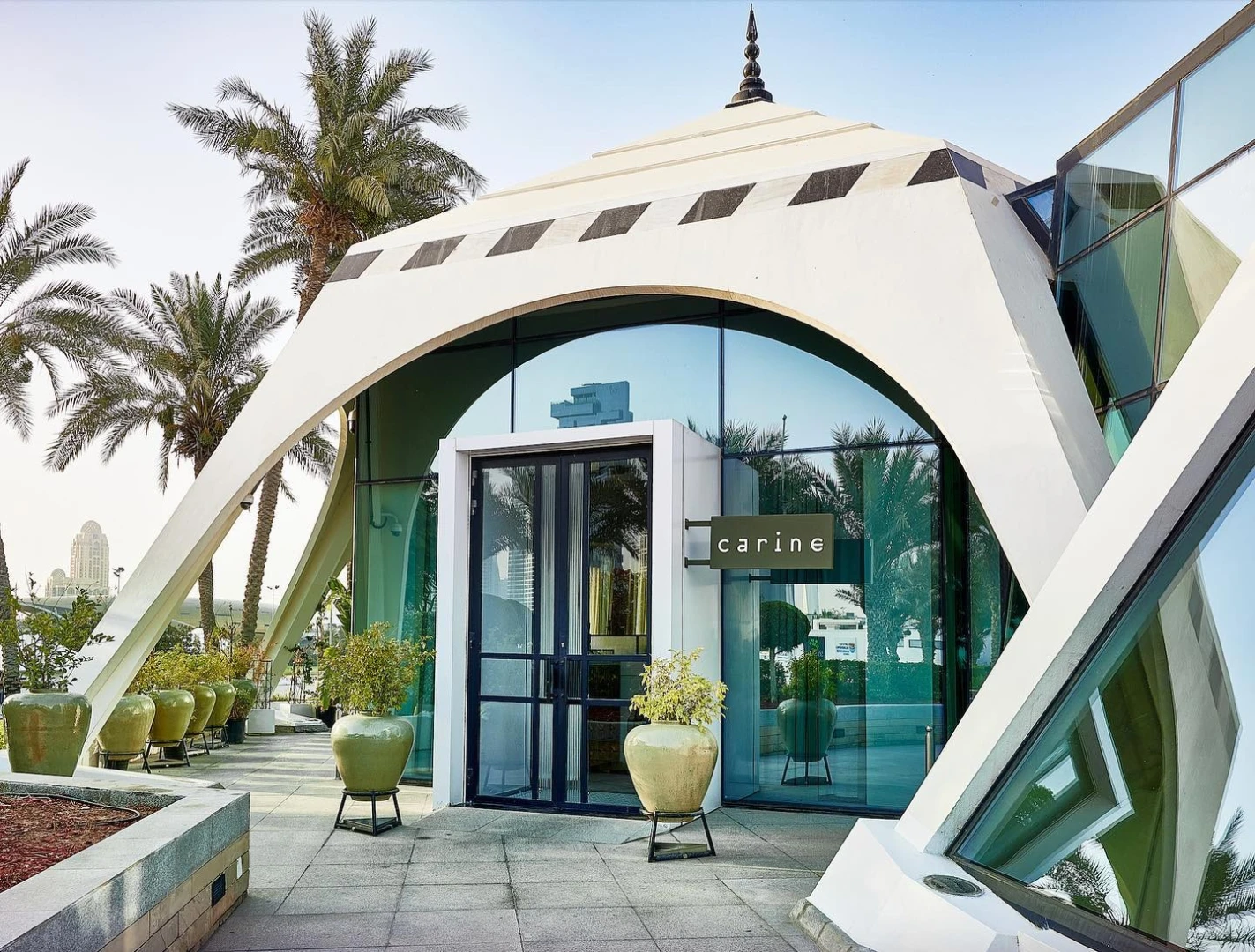 Carine Restaurant Dubai entrance with modern architecture and palm trees.