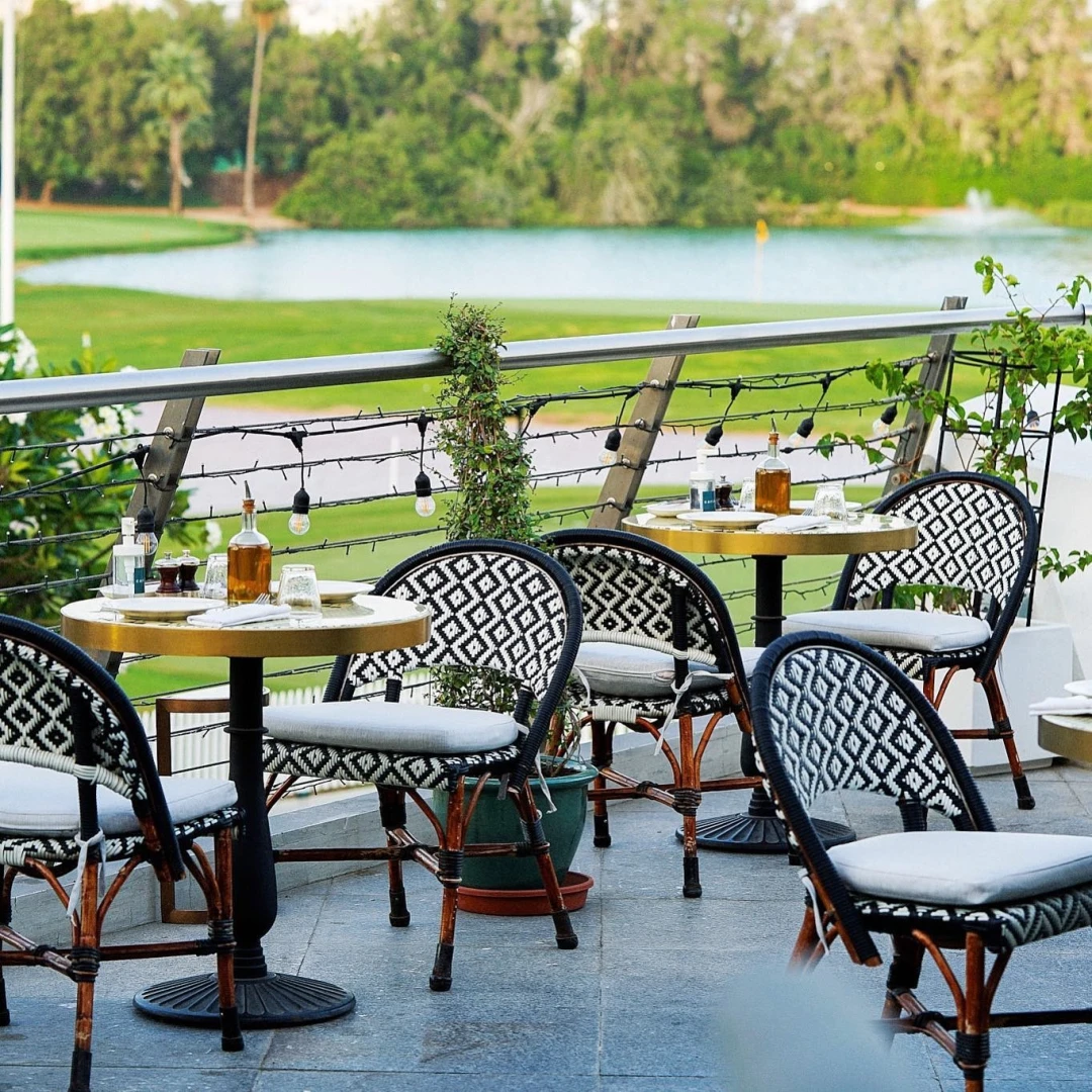 Outdoor seating at Carine Restaurant Dubai overlooking water and greenery.