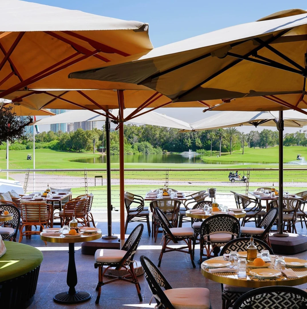 Outdoor dining at Carine Restaurant Dubai overlooking golf course.