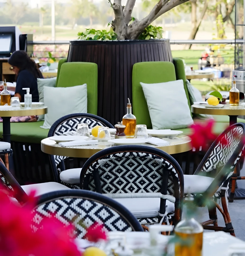 Outdoor seating at Carine Restaurant Dubai with green chairs and tables.