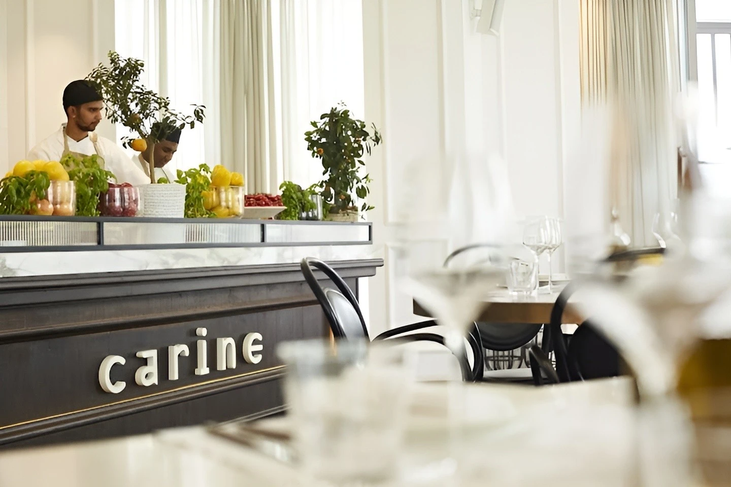 Carine Restaurant Dubai interior with chefs and fresh produce display.