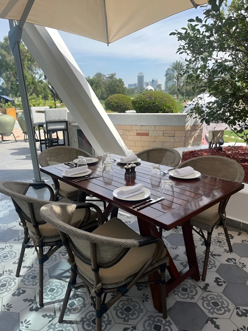 Outdoor dining setup at Carine Restaurant, Dubai with city skyline view.