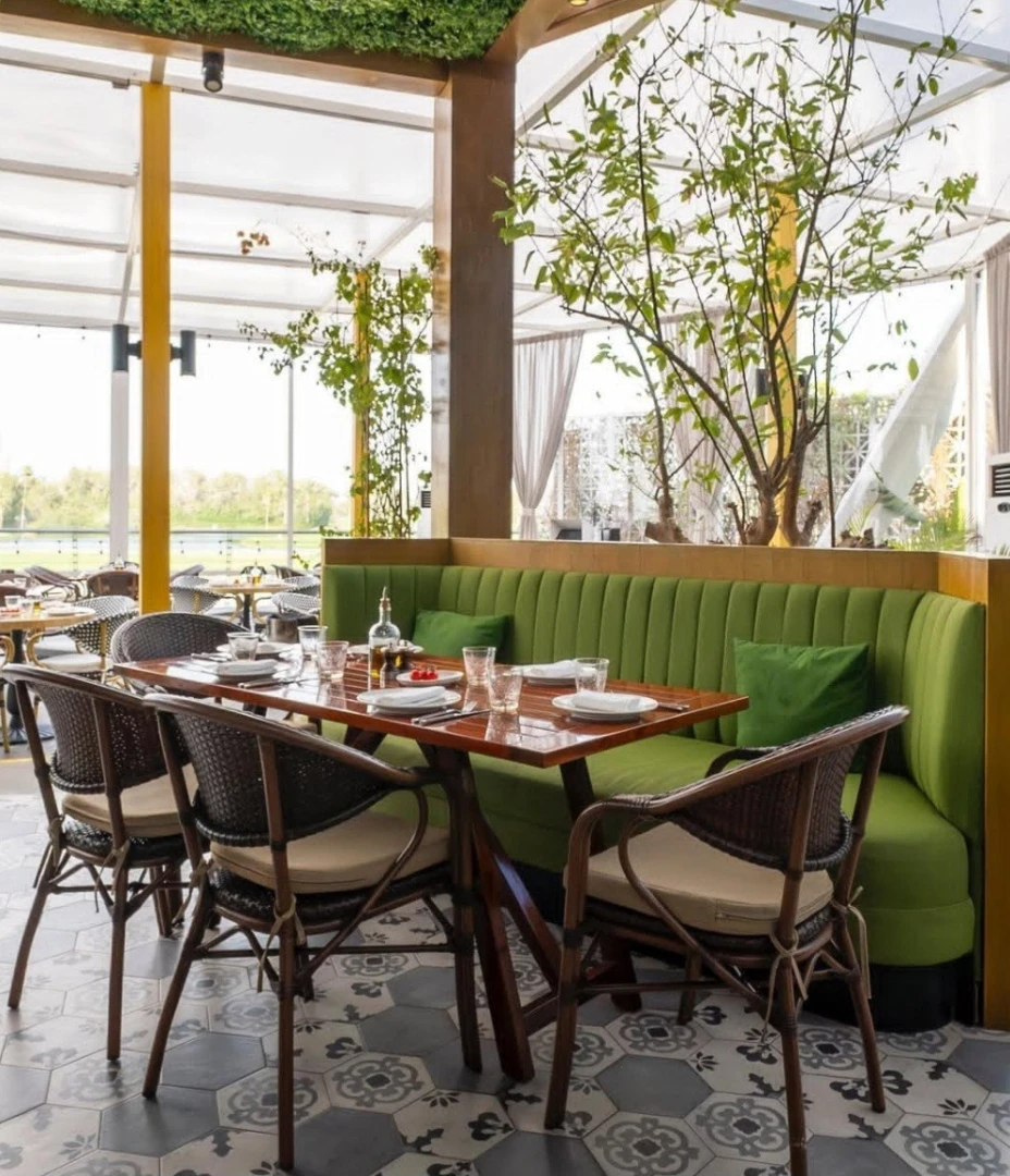 Carine Restaurant Dubai, elegant dining area with green seating and plants.