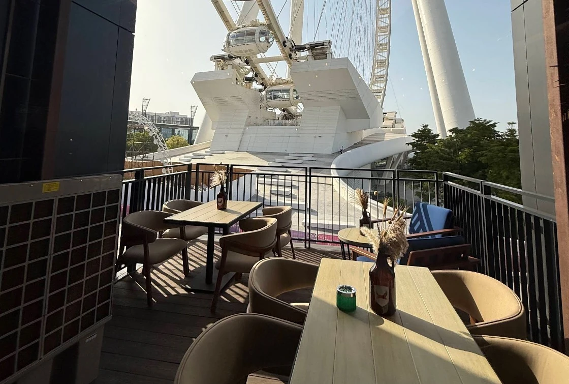 Outdoor seating at BrewDog Bluewaters, Dubai, with Ferris wheel view.