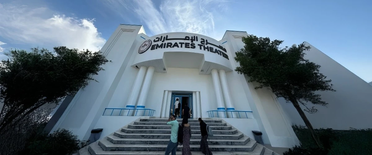 Entrance of Emirates Theatre, Dubai, with people walking up steps.