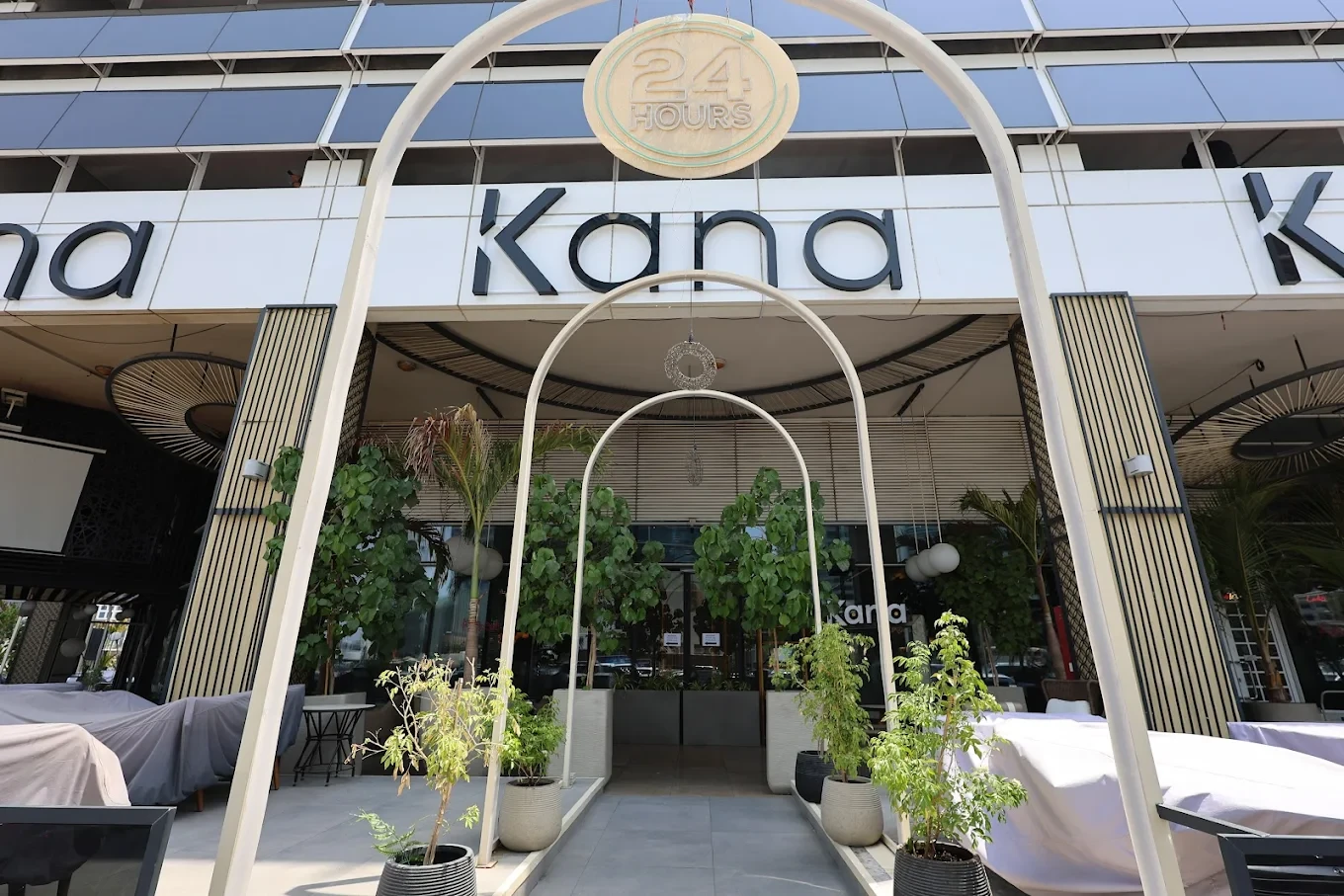 Entrance of The Kana Cafe Downtown Dubai with plants and arches.