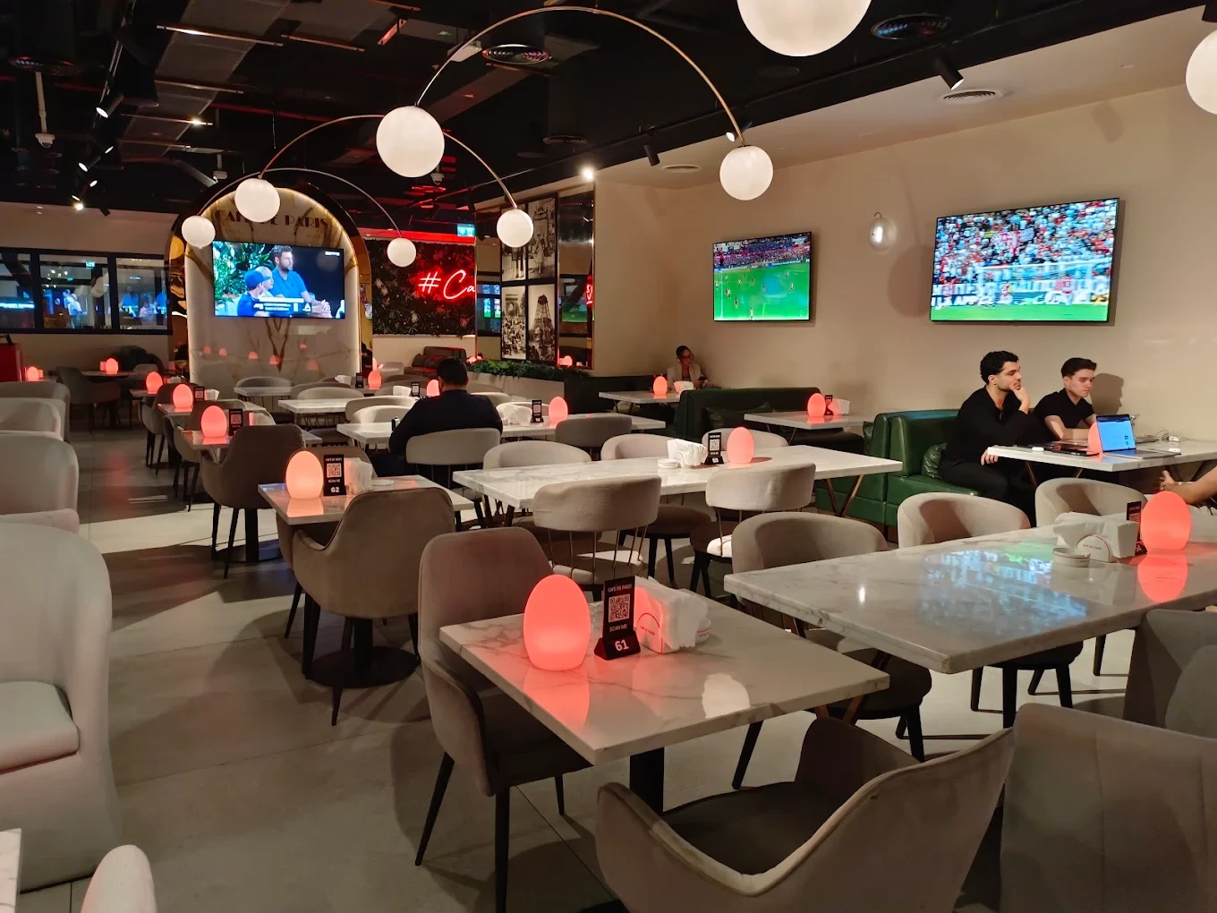Cafe De Paris interior with tables, chairs, and glowing red lights.